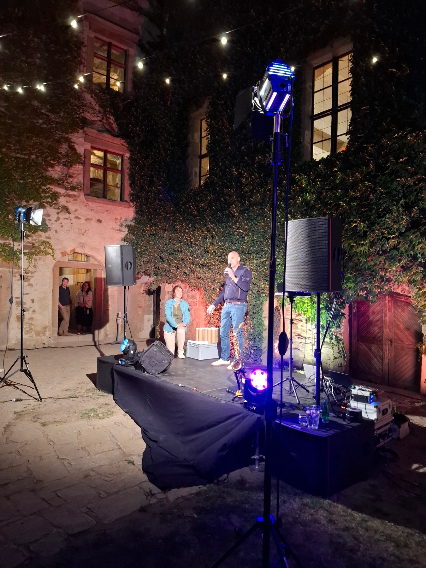 Speaker with a microphone on the stage in the castle courtyard