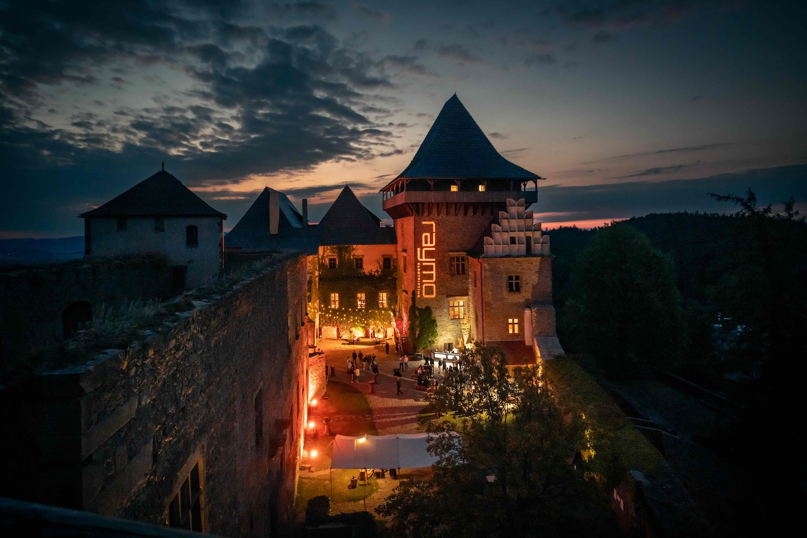 Castle Lipnice at blue hour with the Raymo logo lit on the tower