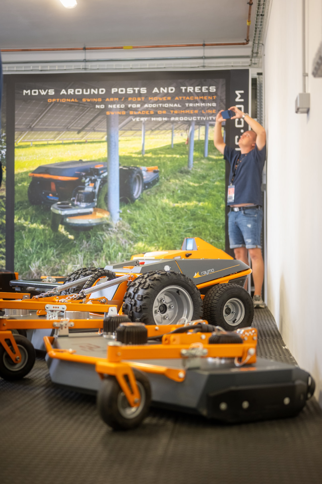 Raymo mower and mowing decks in the showroom next to a product banner