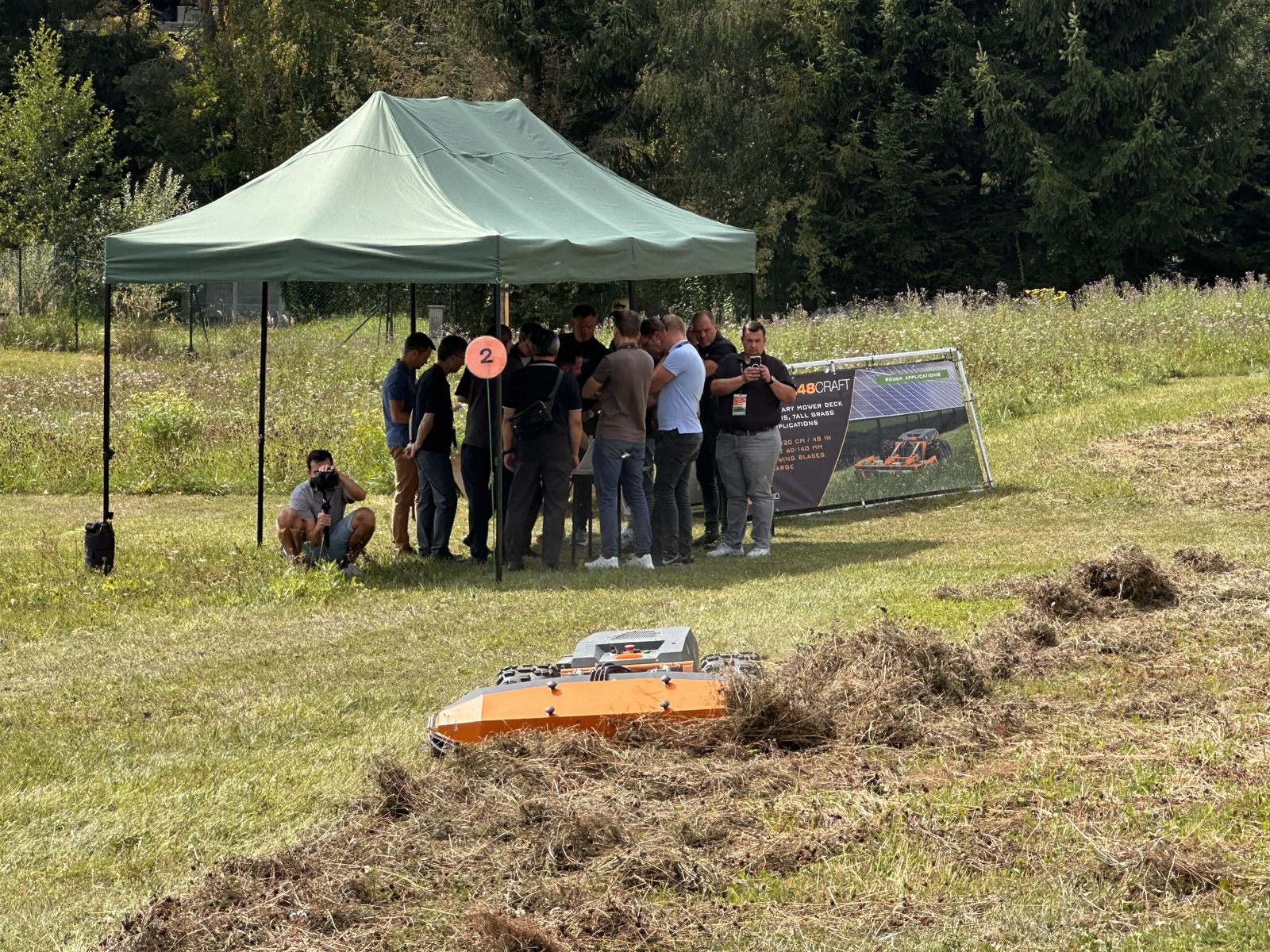 Attendees at demo station 2 with a mower working in the tall grass