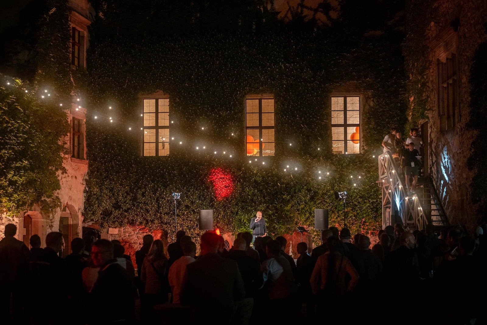 Crowd in the castle courtyard under string lights