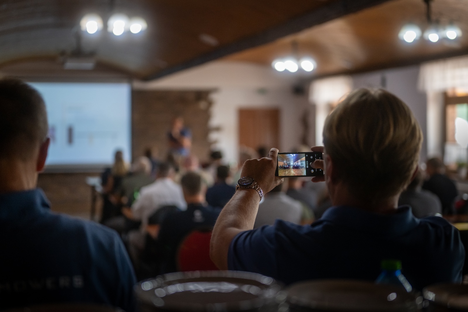 Attendee photographing the presentation with a phone