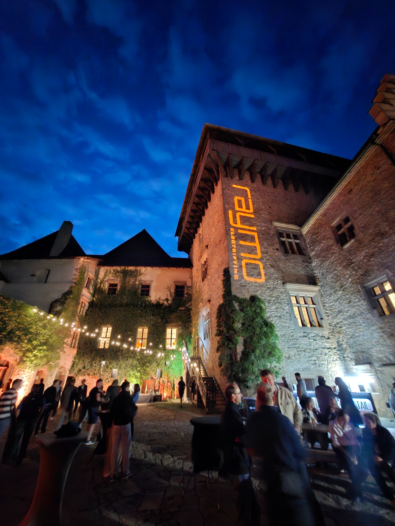 Guests in the castle courtyard under a deep blue evening sky