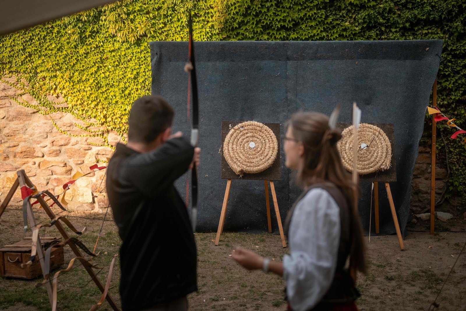 Guest aiming a longbow at straw targets in the castle grounds