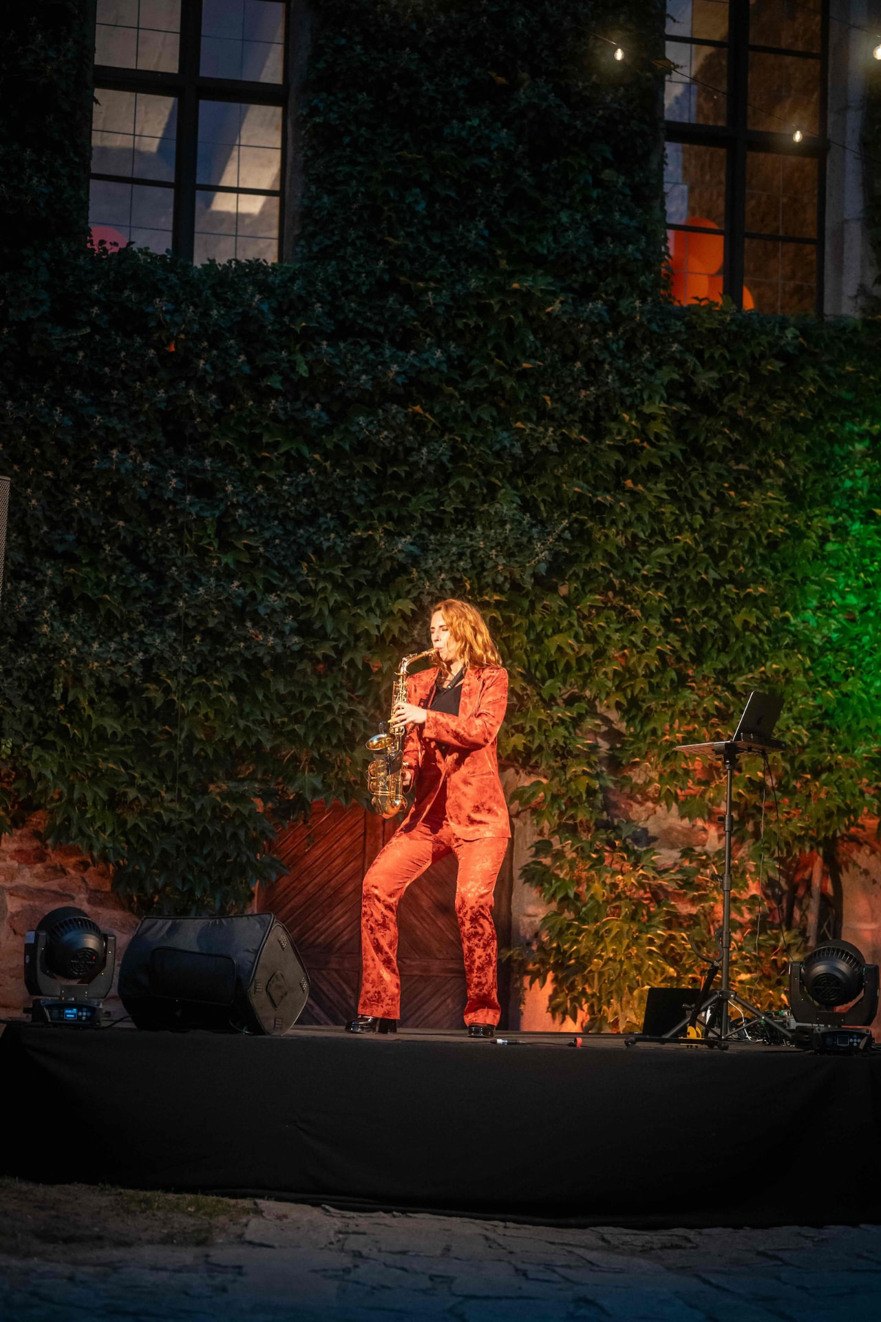Saxophonist playing under string lights on the courtyard stage