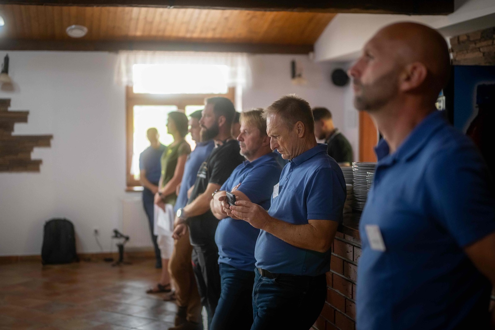 Raymo staff in blue polo shirts standing along the wall during a talk