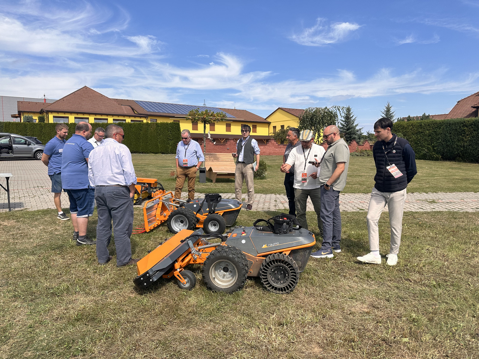 Distributors inspecting Raymo mowers with attachments in front of the hotel