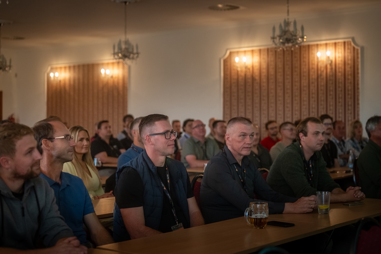 Distributors seated in the hotel conference hall under chandeliers