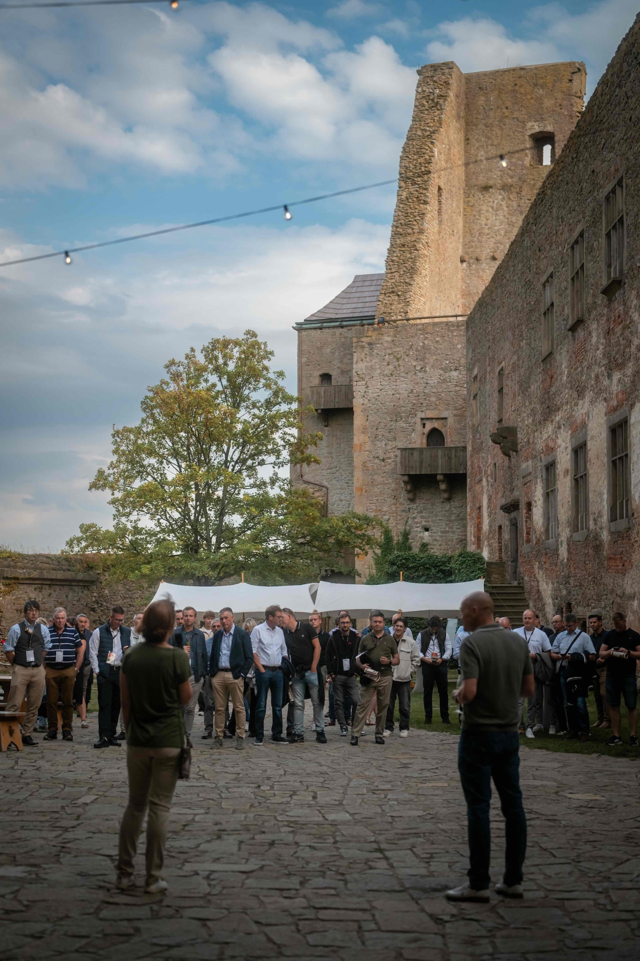 Attendees standing in the courtyard below the castle tower during the programme
